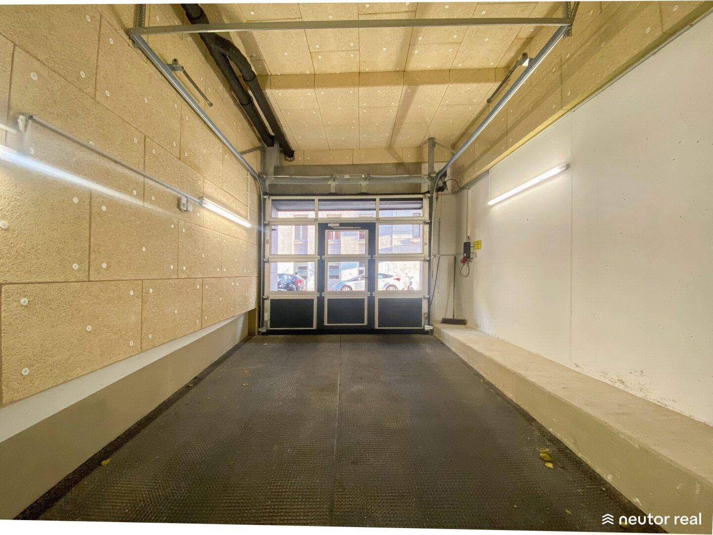 Innenansicht des Ausgangsbereichs der Tiefgarage mit dem Garagentor und Wandverkleidungen.