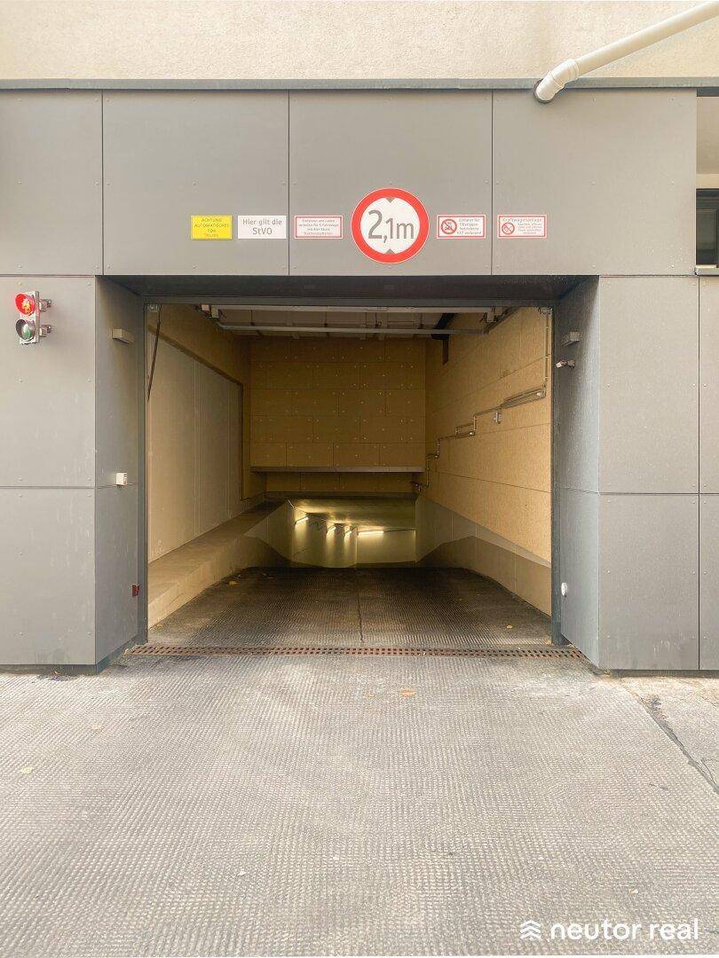 Eingangsbereich einer Tiefgarage mit Höhenbegrenzung von 2,1 Metern und Zufahrtsrampe.