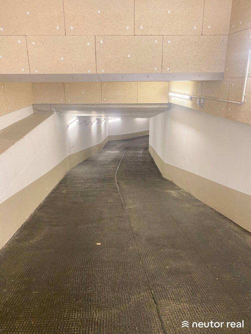 Geschwungene Zufahrtsrampe in der Tiefgarage mit heller Beleuchtung und Wandverkleidung.