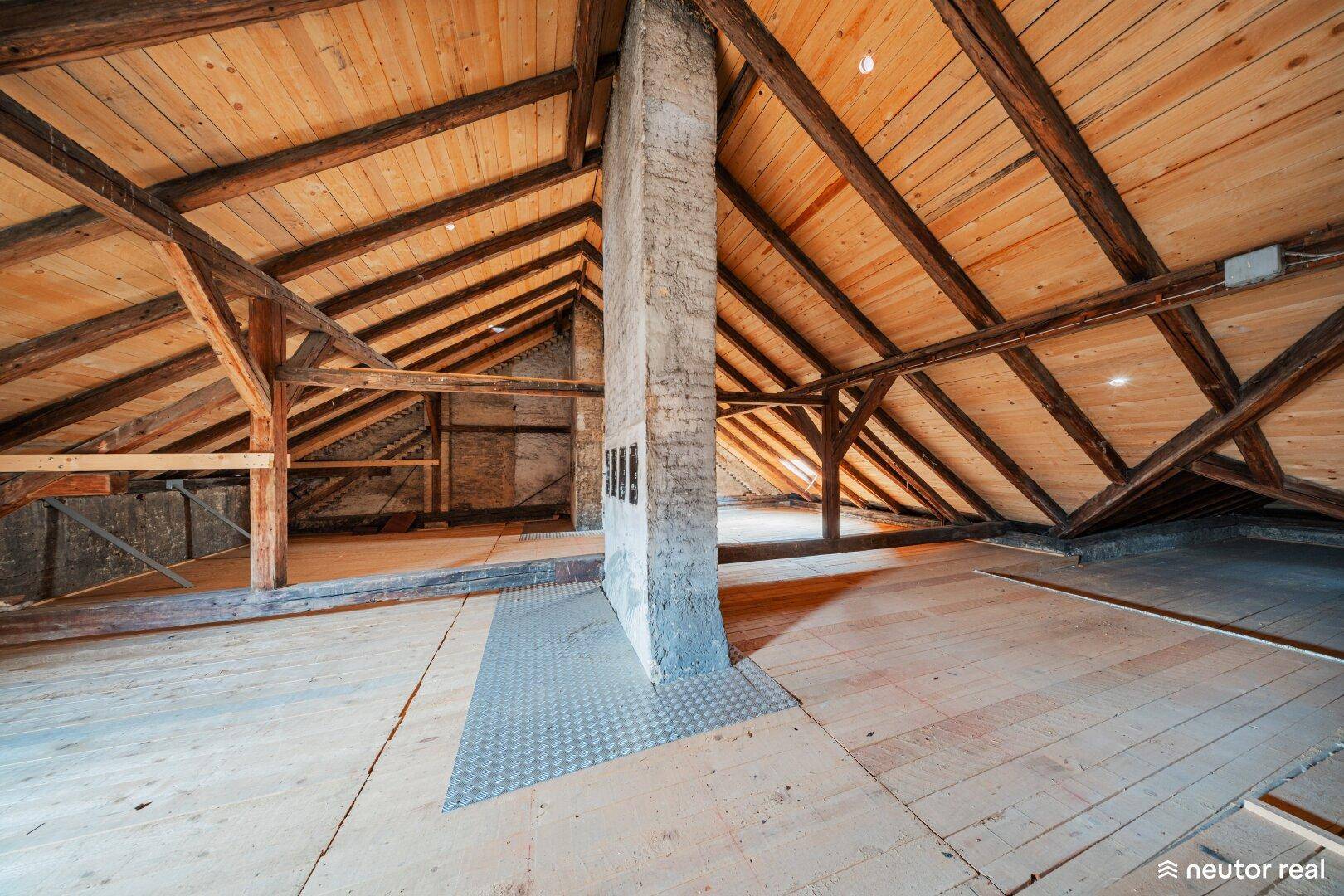 Geräumiger Dachboden mit sichtbaren Holzbalken und schrägen Wänden, bereit für Ausbau.