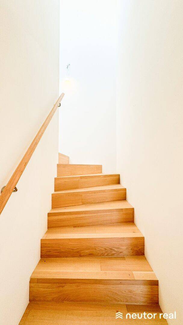 Elegante Holztreppe mit schlichtem Holzgeländer, die in die obere Etage führt.