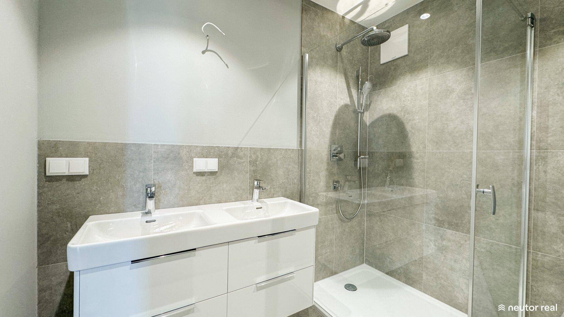 Modernes Badezimmer mit Doppelwaschbecken, großer Spiegelfläche und begehbarer Dusche mit Regenduschkopf.