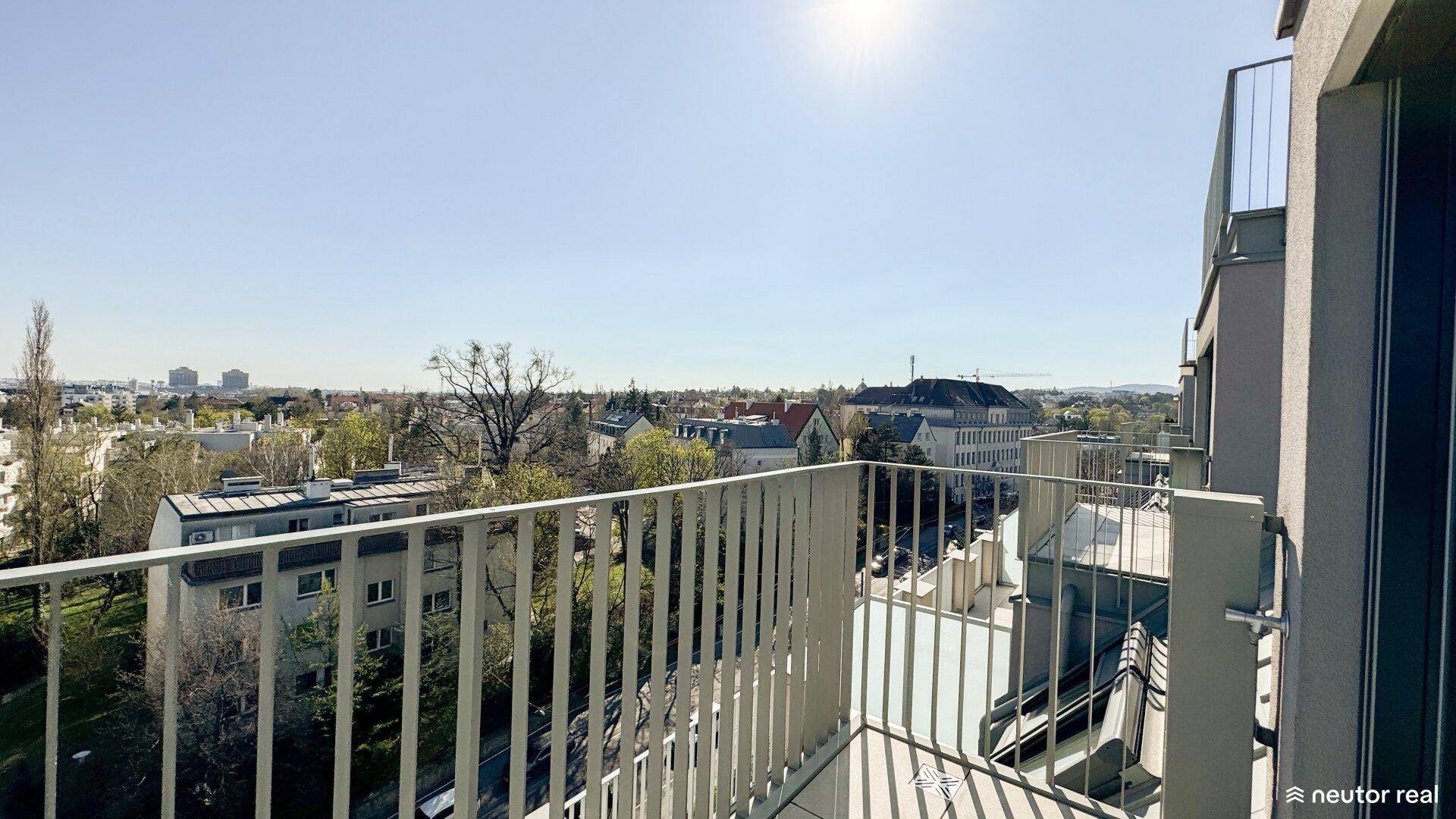 Sonniger Balkon mit Panoramablick über die Stadt und die umliegende grüne Landschaft.