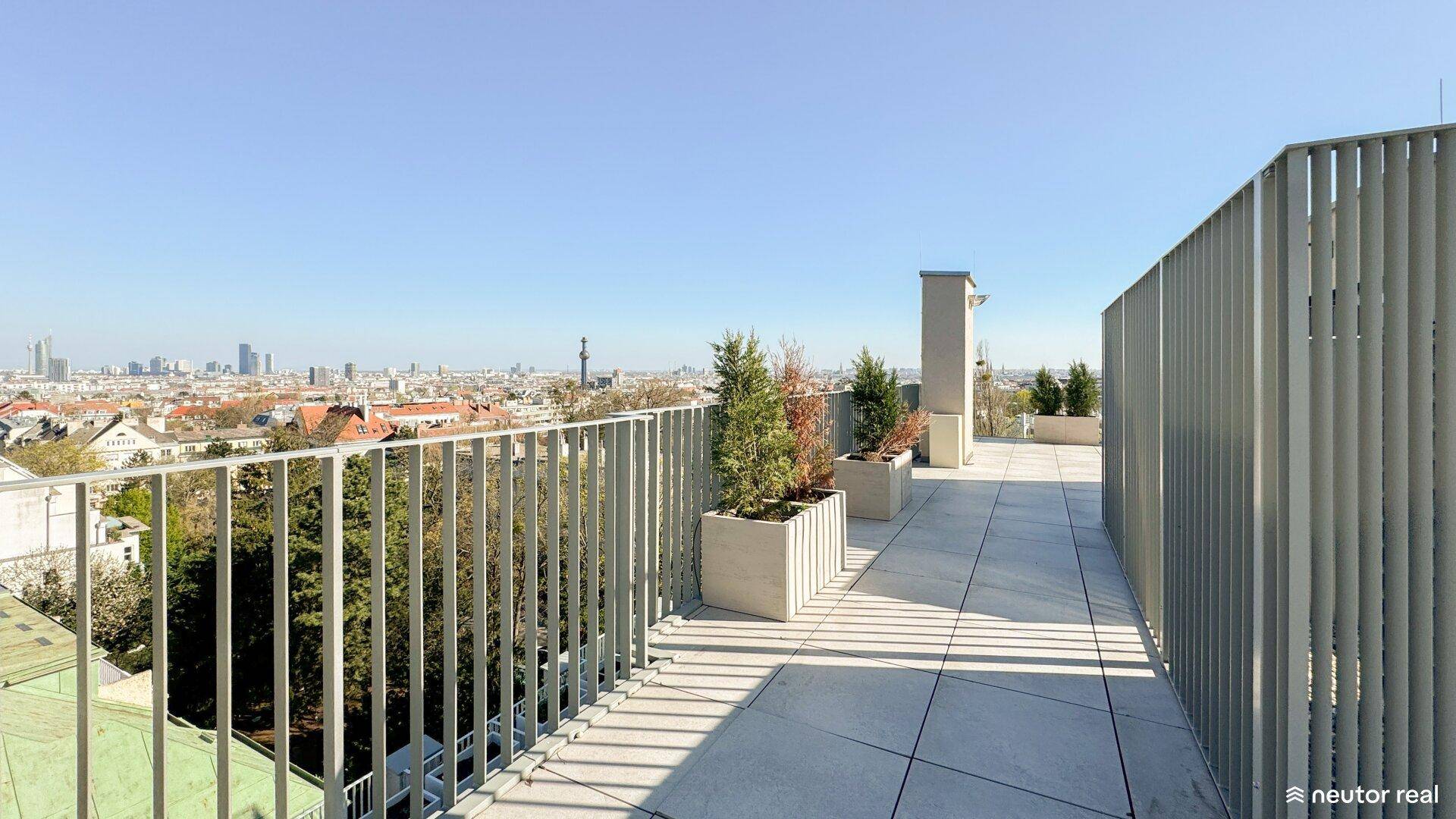 Dachterrasse mit Pflanzen und weitem Blick auf die Stadt und ihre beeindruckende Skyline.