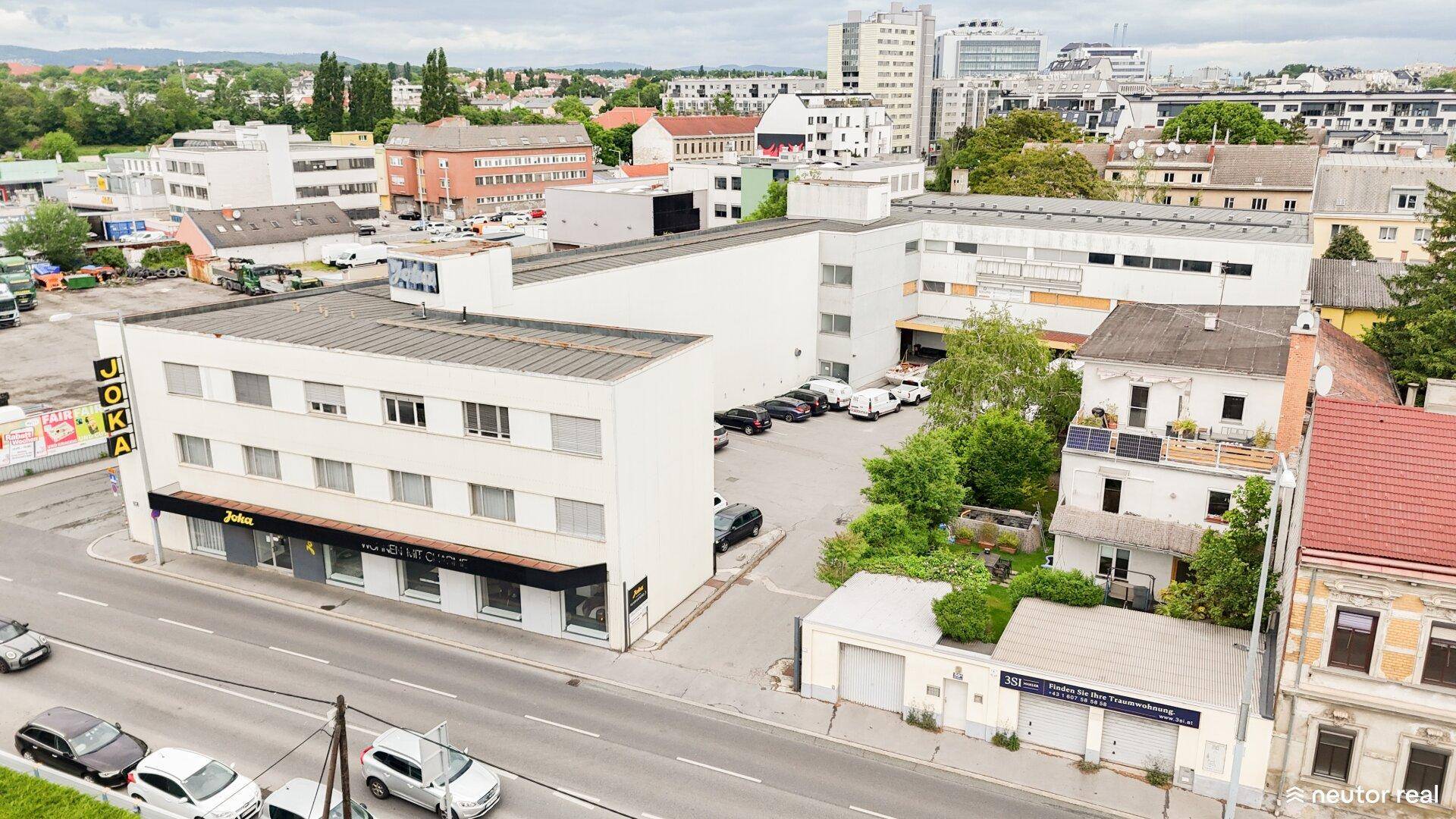 Luftaufnahme eines modernen Geschäftsgebäudes mit Parkplätzen in einer städtischen Umgebung.