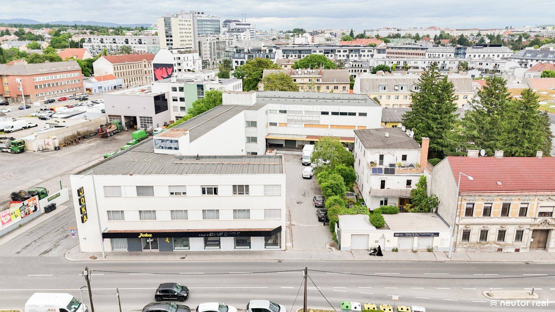 Übersicht aus der Vogelperspektive auf das Gewerbeobjekt und die städtische Umgebung mit viel Grün.