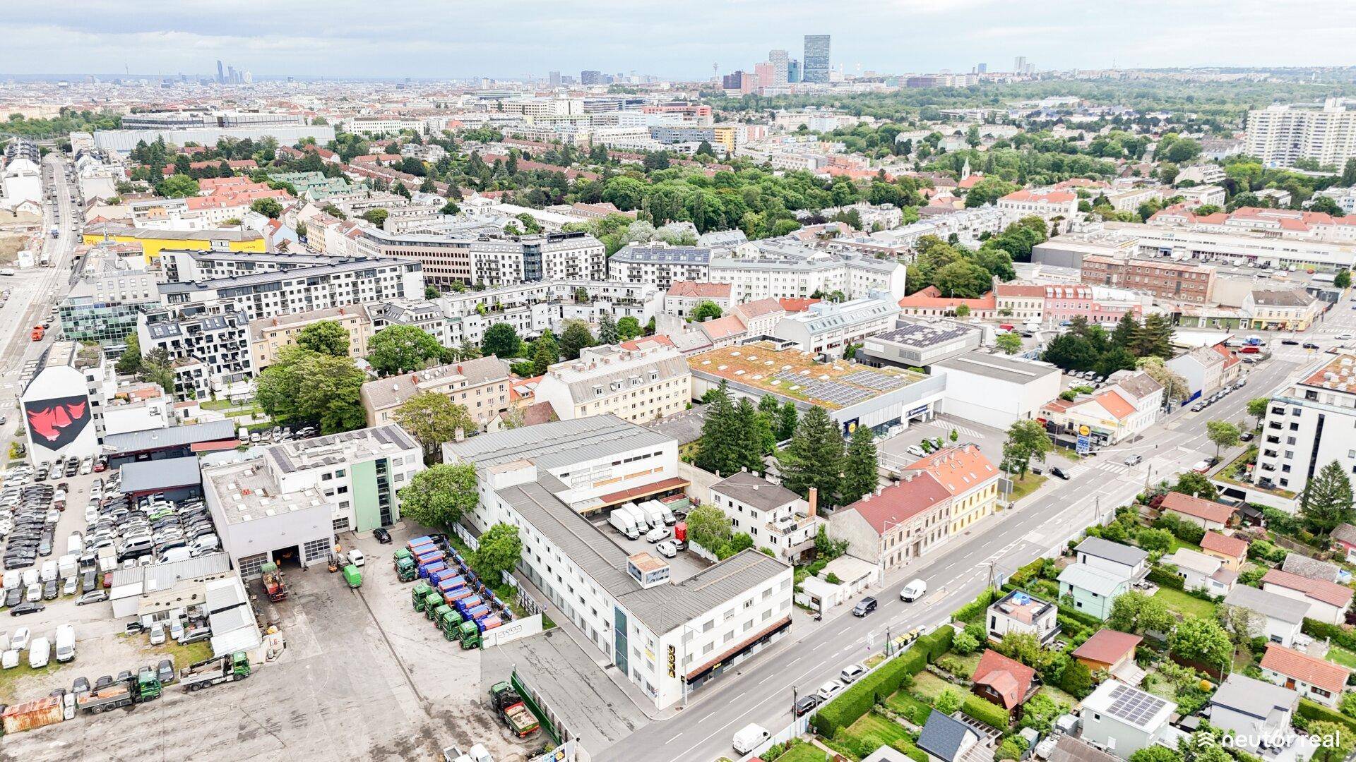 Weitläufige Luftaufnahme eines städtischen Gebiets mit verschiedenen Gebäudetypen und viel Grün.