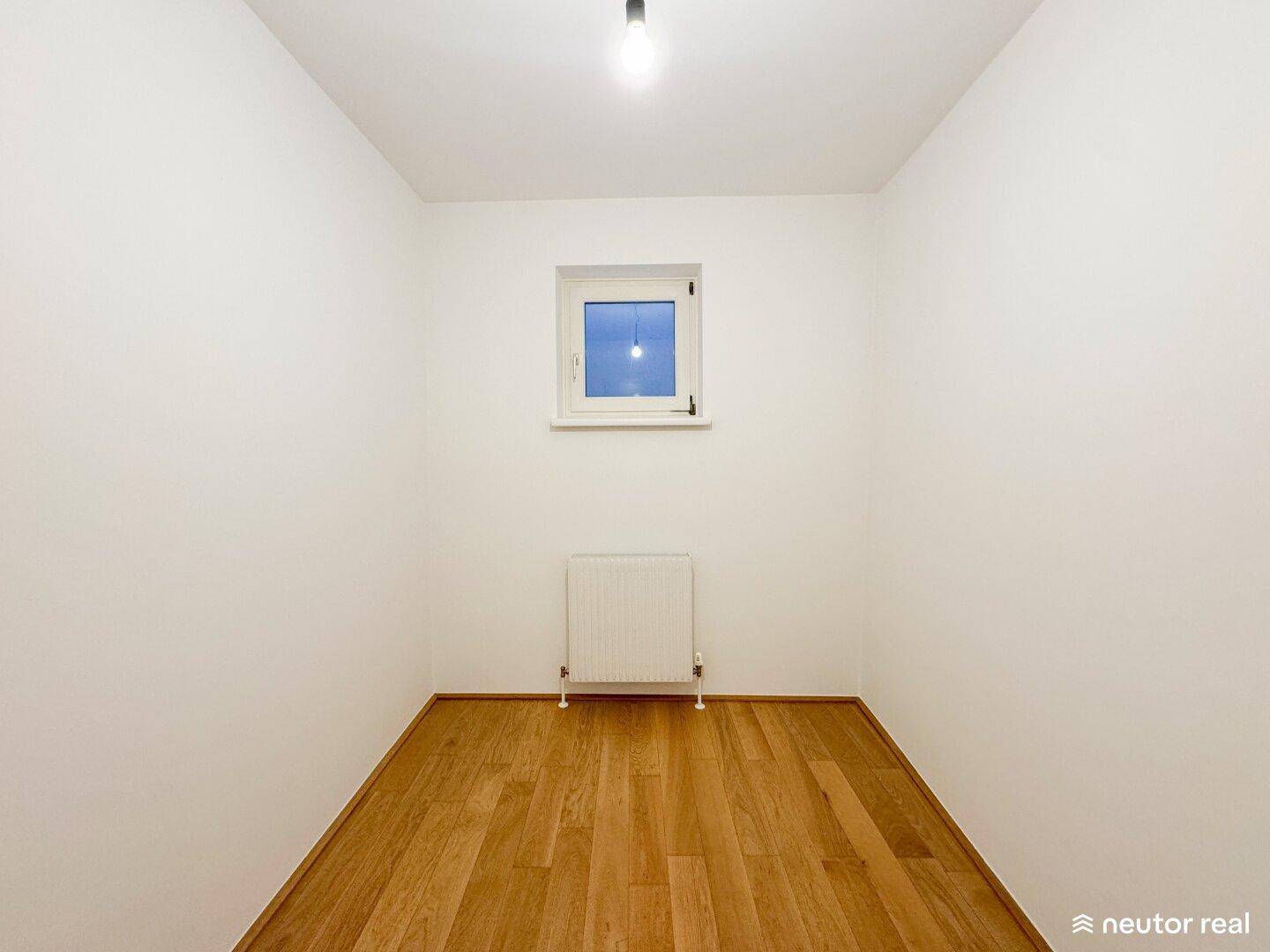 Kleines, helles Zimmer mit Holzboden und Fenster, ideal als Büro oder Kinderzimmer.