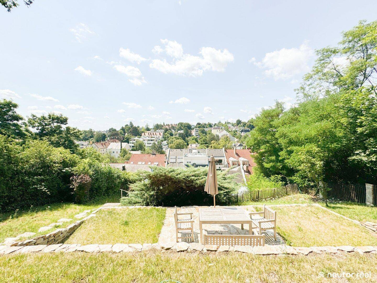 Sonniger Gartenbereich mit Sitzgelegenheiten und weitem Blick über die umliegende Wohnsiedlung.