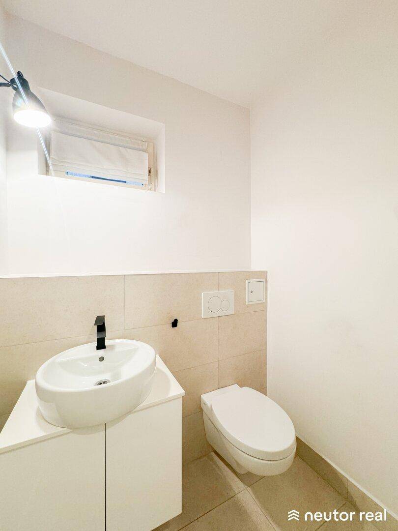 Modernes Gäste-WC mit elegantem Waschbecken und wandhängender Toilette in hellen Farbtönen.