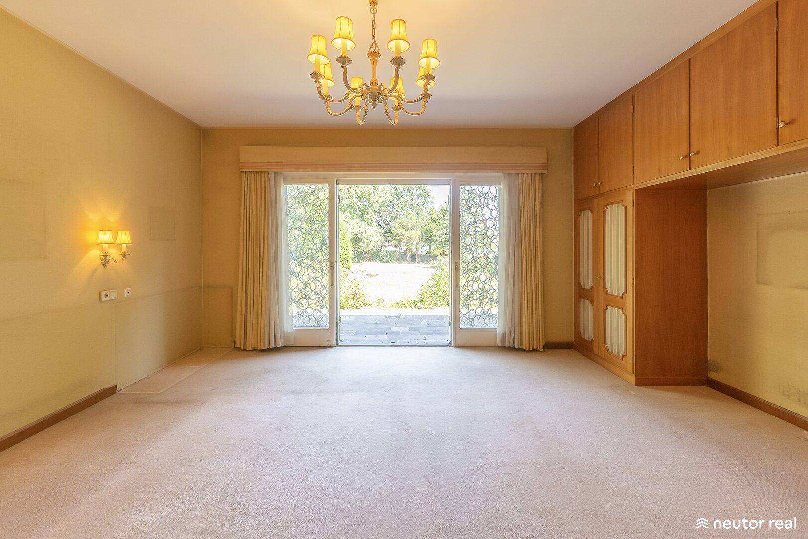 Geräumiges Schlafzimmer mit Teppichboden und großen Fenstern zum Garten.