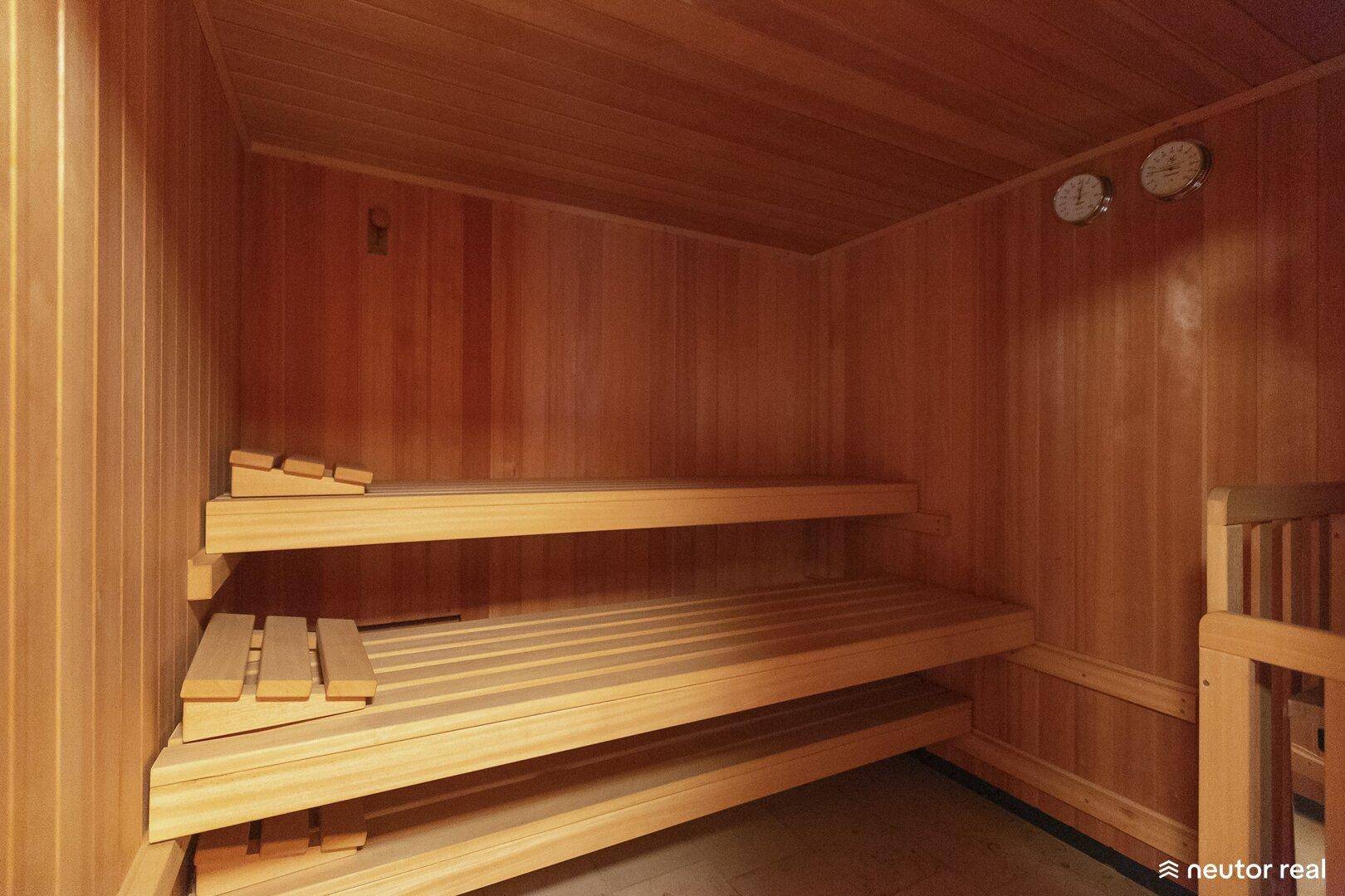 Traditionelle Holzsauna mit mehrstufigen Bänken und Temperaturanzeigen.