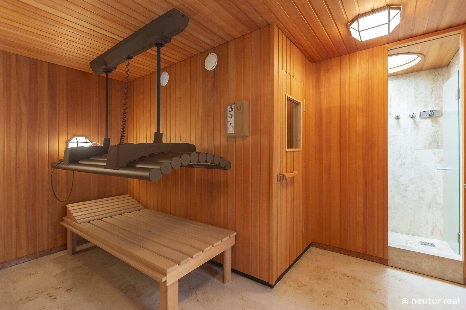 Wellnessbereich mit Holzverkleidung, Solarium und Zugang zu einer Dusche.