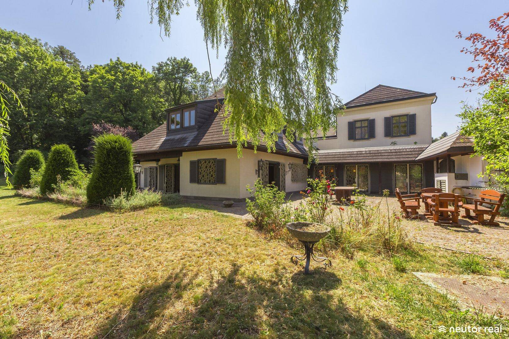 Charmante Terrasse mit rustikalen Holzmöbeln und Blick auf den weitläufigen Gartenbereich des Anwesens.