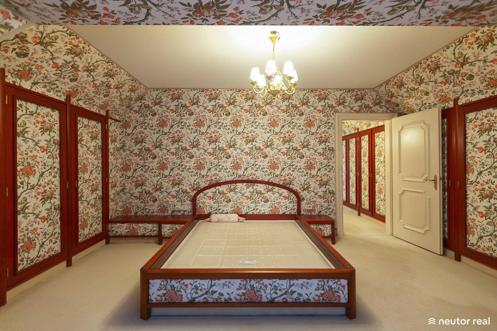 Schlafzimmer mit floraler Tapete, Teppichboden und passenden Einbauschränken.