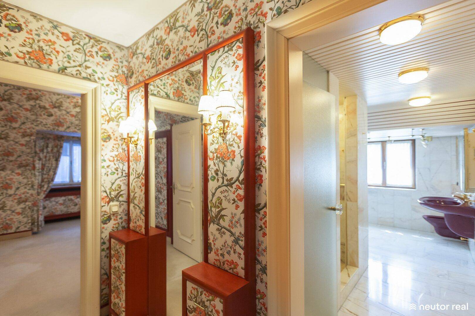 Flur mit floraler Tapete und Zugang zu einem Badezimmer mit Marmor.