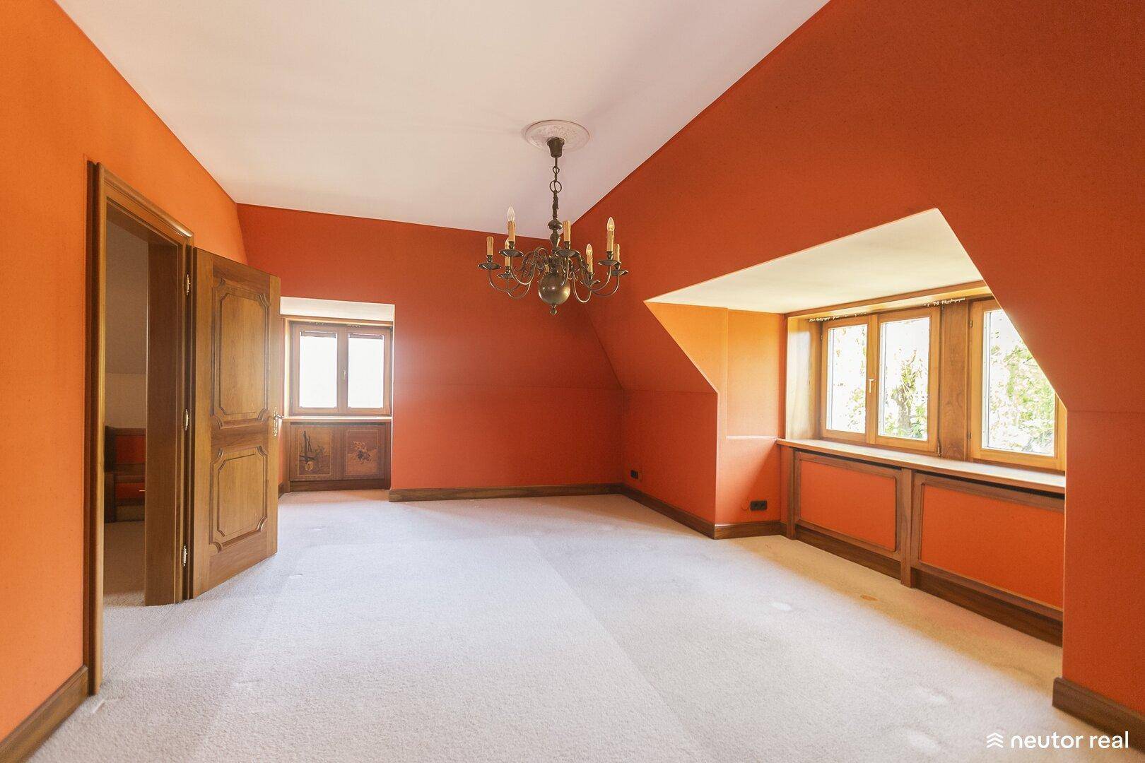 Geräumiges Schlafzimmer mit orangefarbenen Wänden, Teppichboden und Dachschräge.