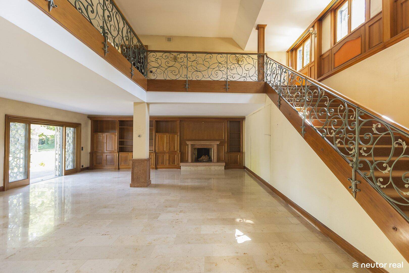 Großzügiger Wohnbereich mit Marmorboden, hoher Decke und eleganter Treppe.