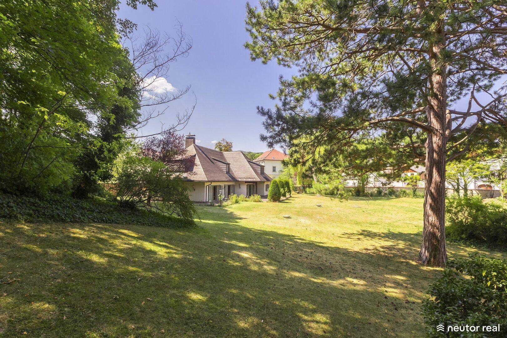 Weitläufiger Garten mit altem Baumbestand und Blick auf das charmante Landhaus in der Ferne.