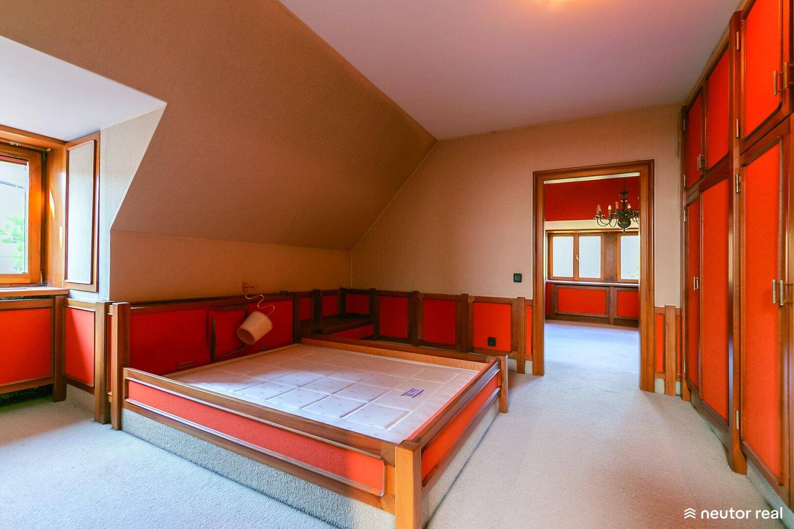 Schlafzimmer mit Dachschrägen, integriertem Bett und orangefarbenen Akzenten.