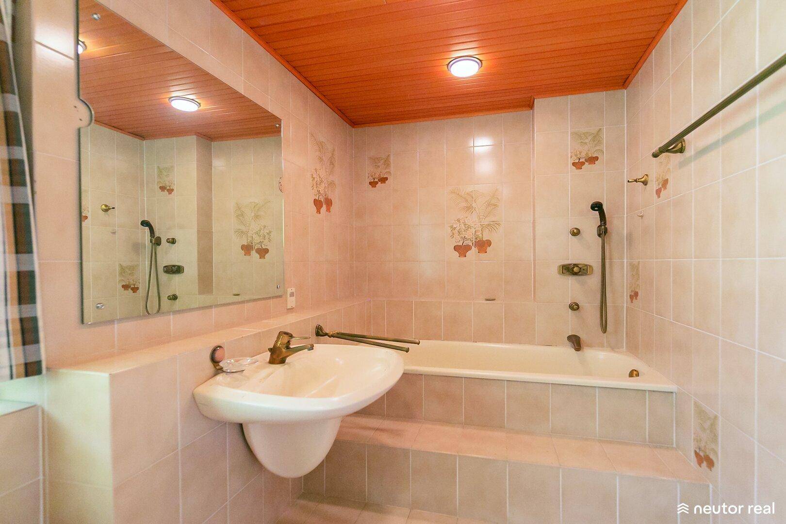 Badezimmer mit beigefarbenen Fliesen, Holzdecke, Badewanne und Waschbecken.