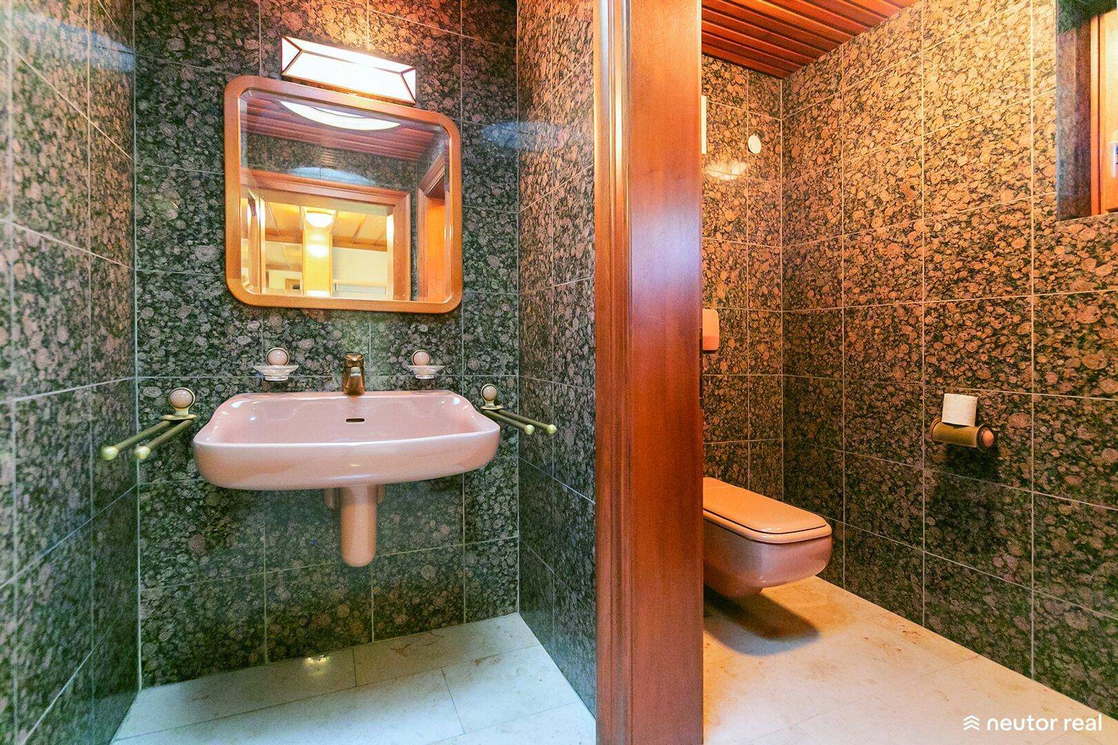 Gäste-WC mit dunklen Granitfliesen, Holzdecke und rosa Waschbecken.