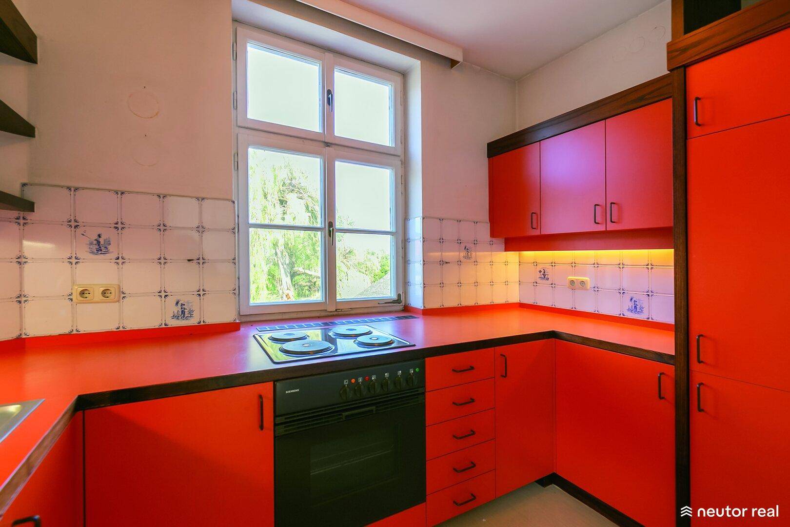 Funktionale Küche mit leuchtend roten Schränken und integriertem Herd und Backofen.