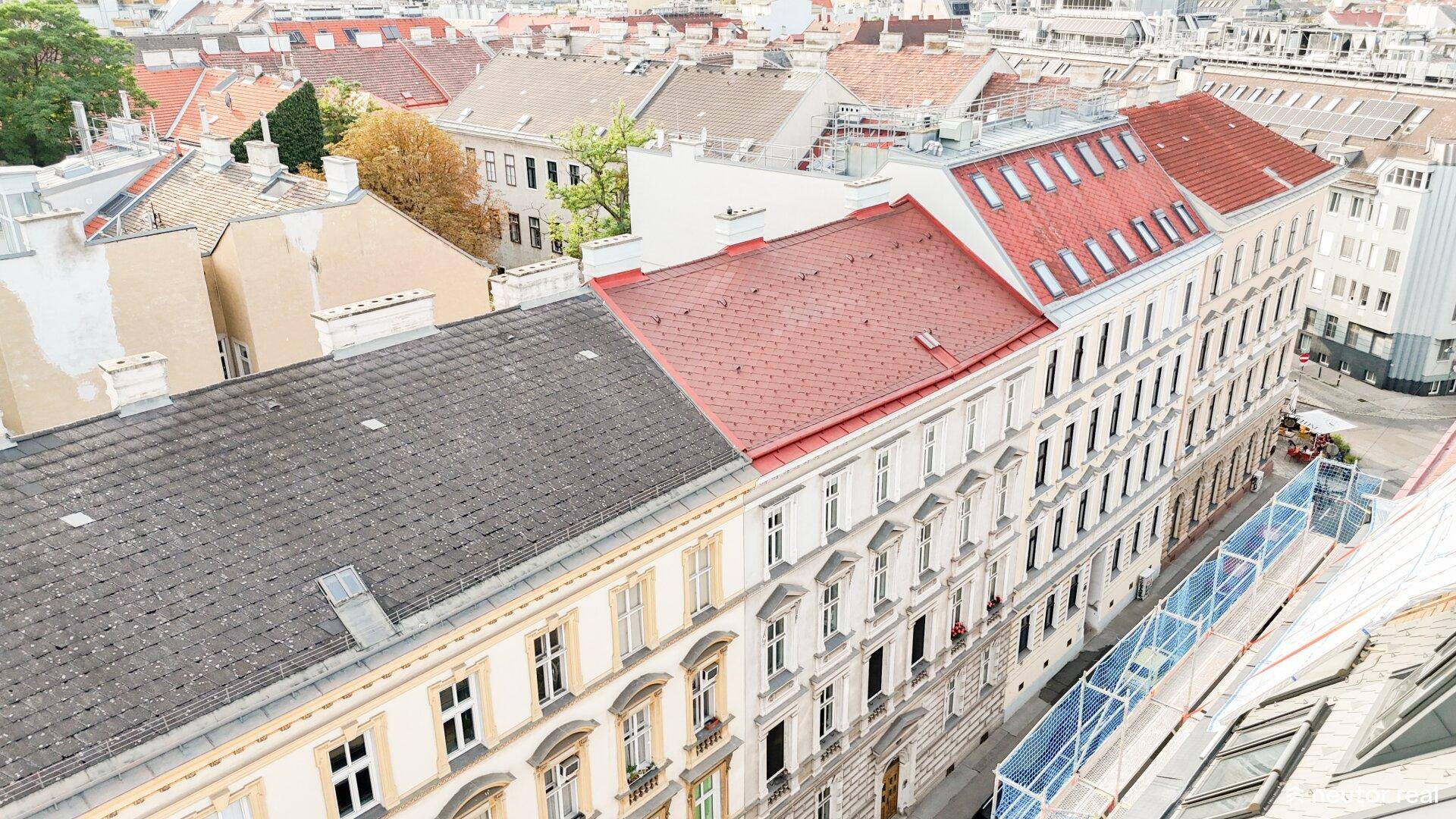 Dachlandschaft einer Stadt mit verschiedenen Gebäuden und roten Ziegeldächern aus der Vogelperspektive.