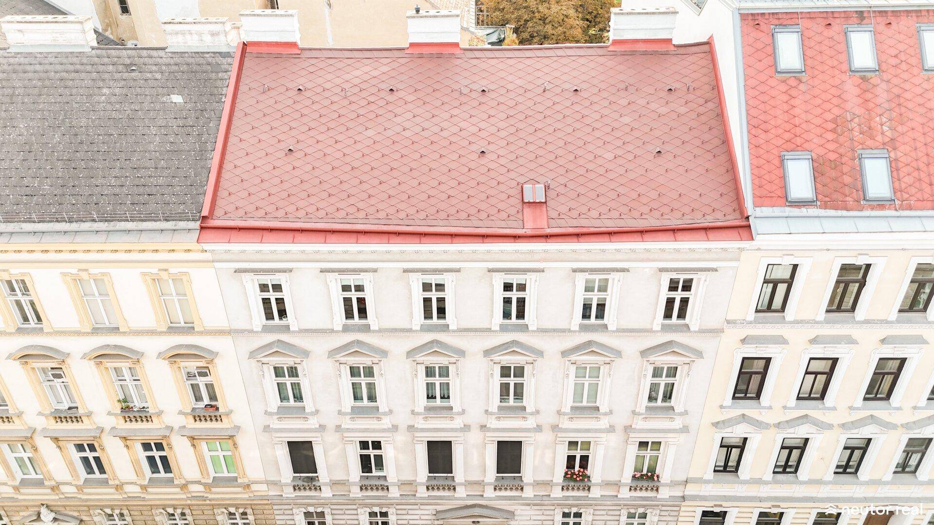 Vertikale Ansicht von Gebäudefassaden mit vielen Fenstern und roten Ziegeldächern in der Stadt.