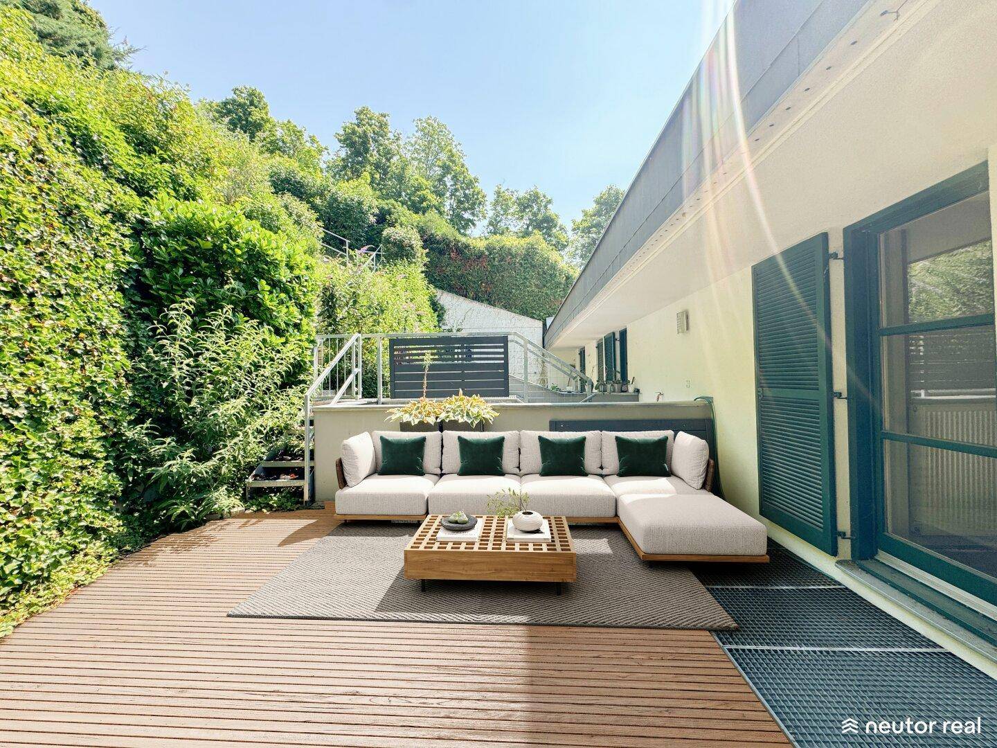 Großzügige Holzterrasse mit moderner Lounge-Sitzgruppe und üppiger Bepflanzung für entspannte Stunden.