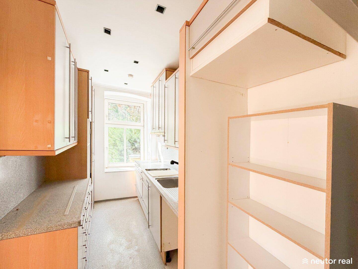 Schmale Küche mit weißen und holzfarbenen Schränken, bereit für eine Modernisierung.