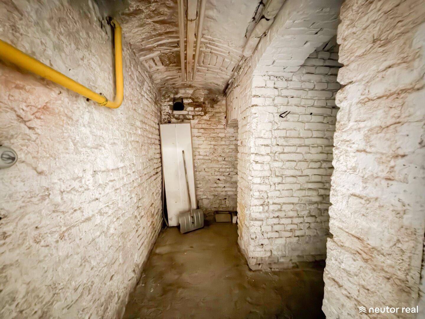 Historischer Kellerraum mit unverputzten Ziegelwänden und sichtbaren Leitungen, ideal als Lagerfläche.