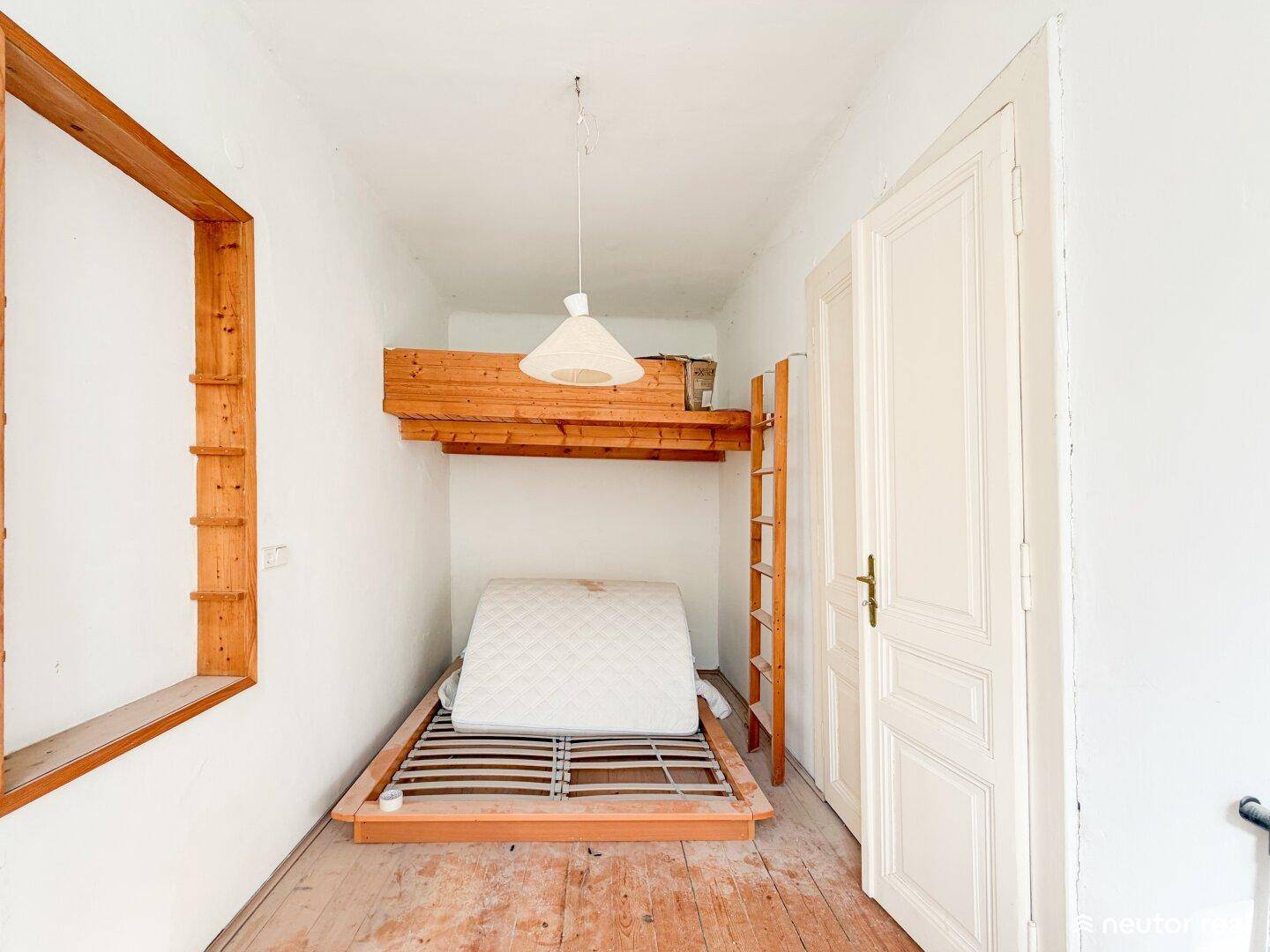 Helles Schlafzimmer mit Holzboden, Bettgestell und einer Holzkonstruktion für ein Hochbett.