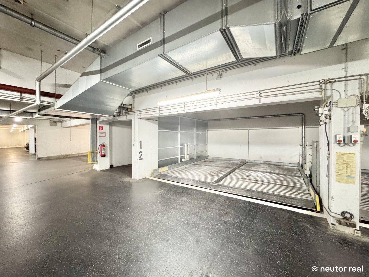 Weitläufige Tiefgarage mit mehreren automatischen Parksystemen und guter Beleuchtung.