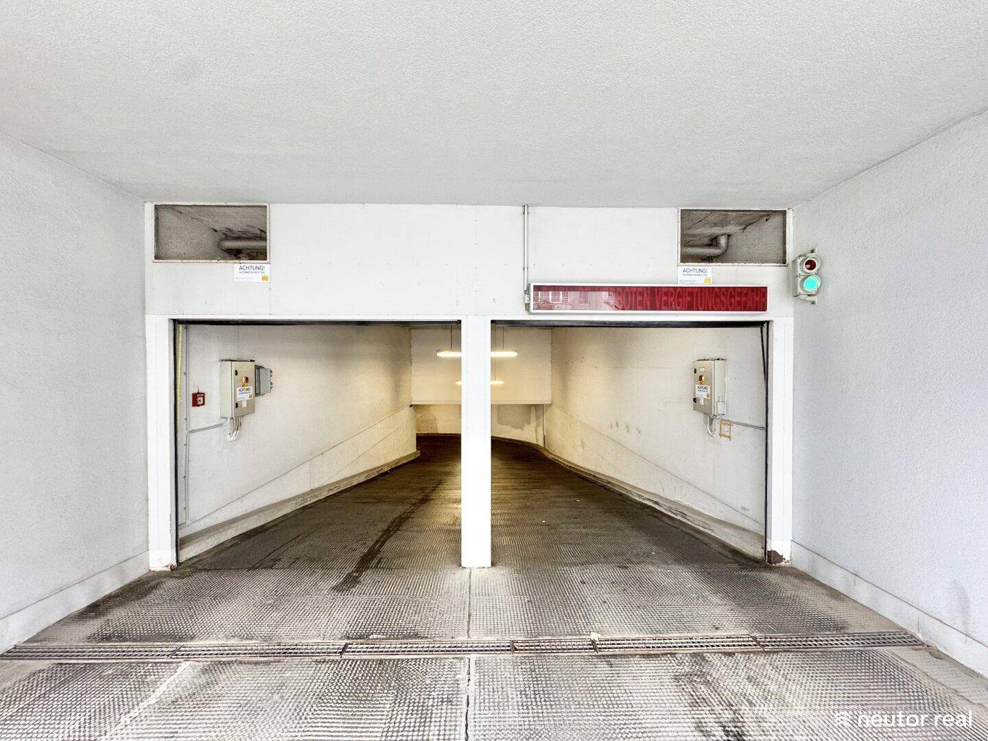 Zwei Einfahrtsrampen zu einer Tiefgarage, gut beleuchtet und mit Verkehrssignalen ausgestattet.