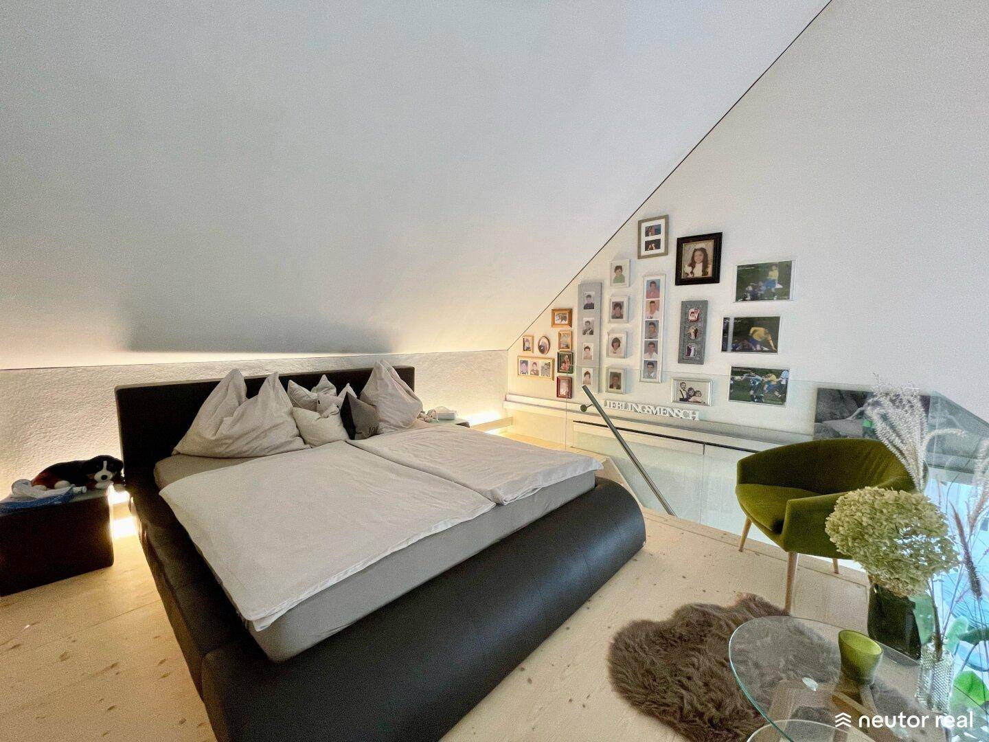 Schlafzimmer auf der Galerie mit schrägen Wänden, Doppelbett und Blick auf den unteren Wohnbereich.