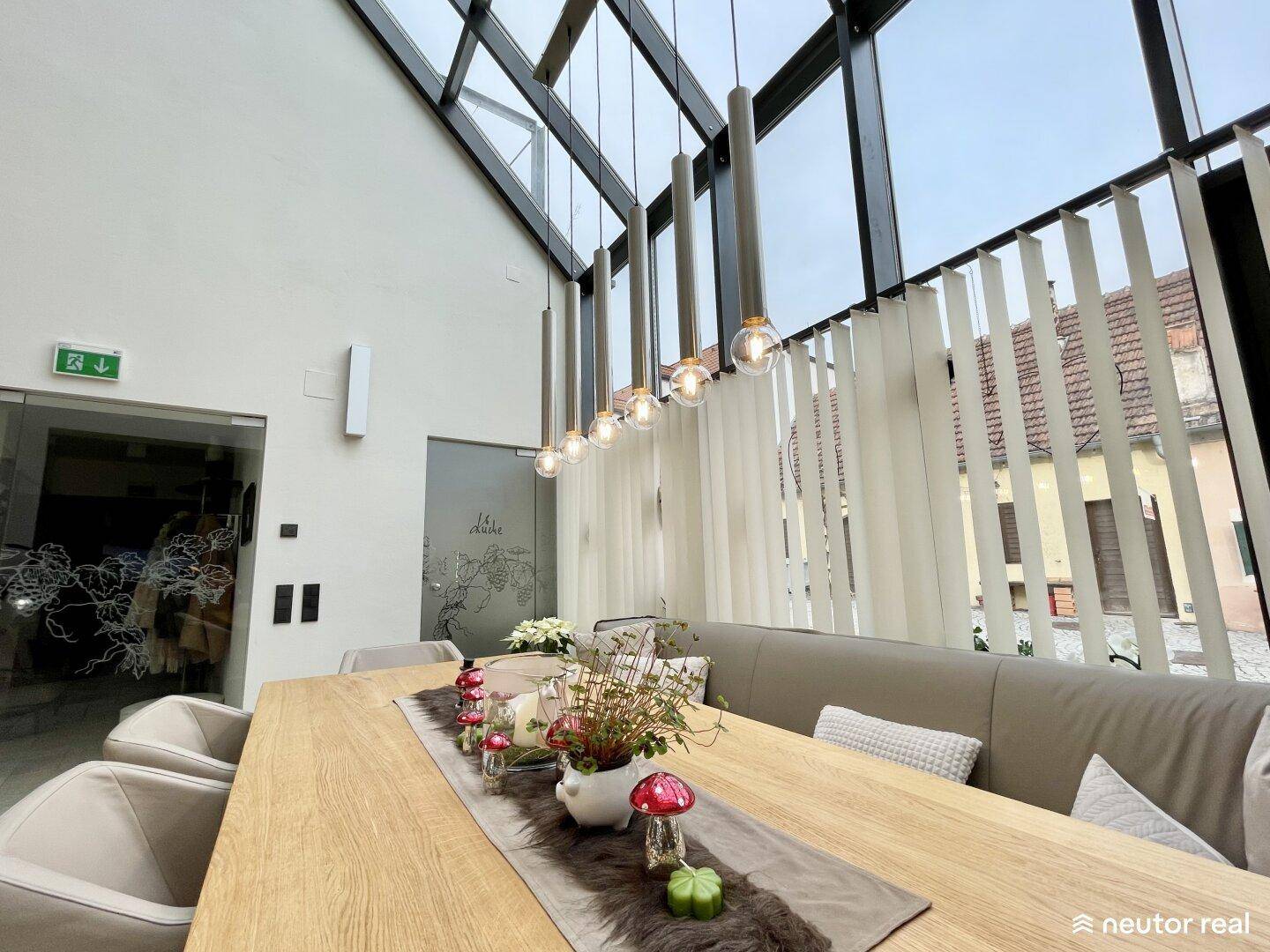 Moderner Essbereich mit langem Holztisch, bequemen Sitzgelegenheiten und einer beeindruckenden Glasfront.