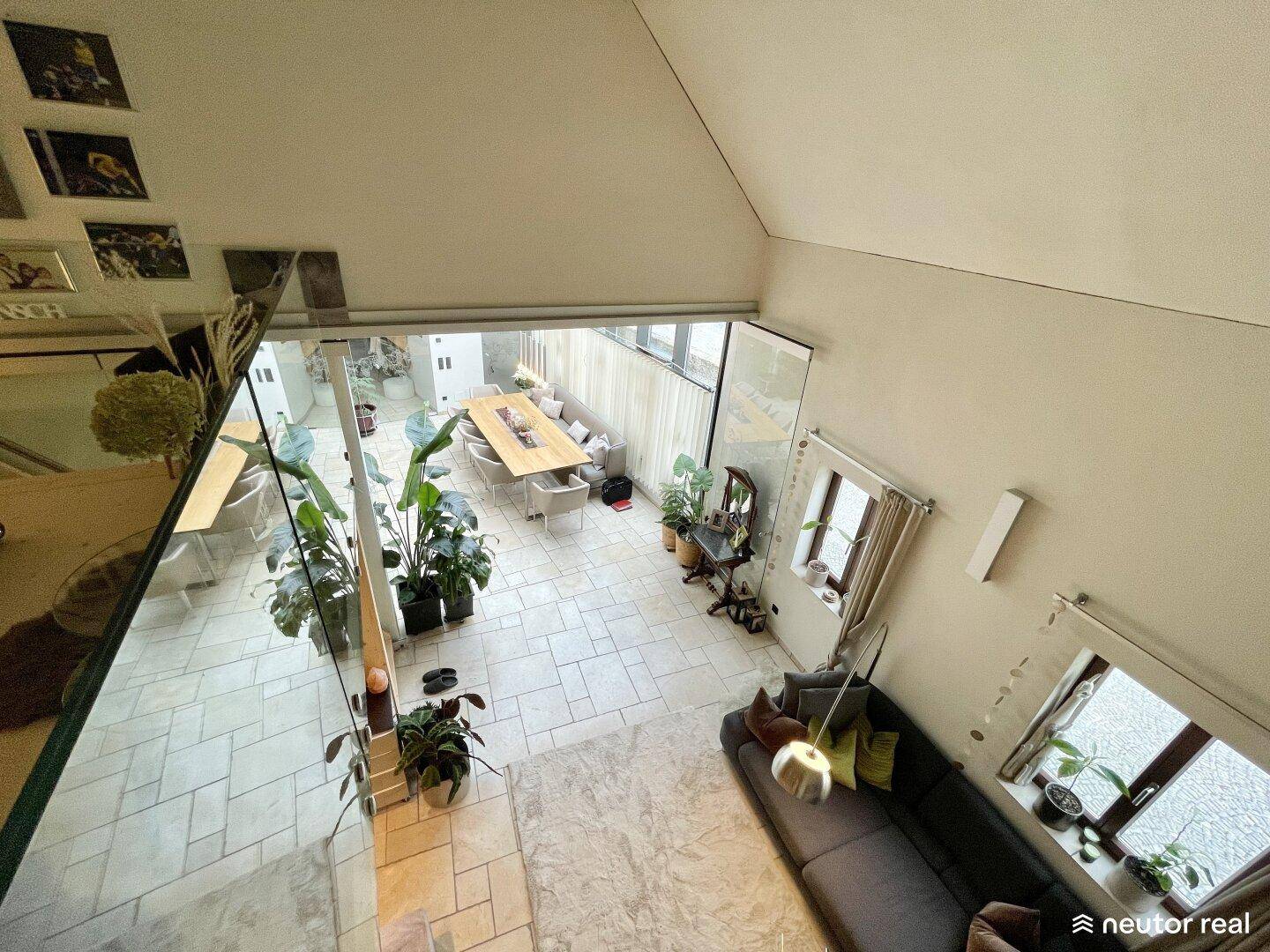 Weitblick von der Galerie über den offenen Wohn- und Essbereich mit hohen Decken und Glasfront.