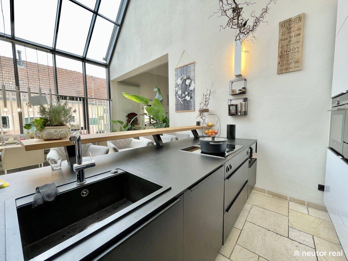 Moderne Küche mit dunklen Arbeitsplatten, integriertem Kochfeld und Spüle, offen zum Essbereich.