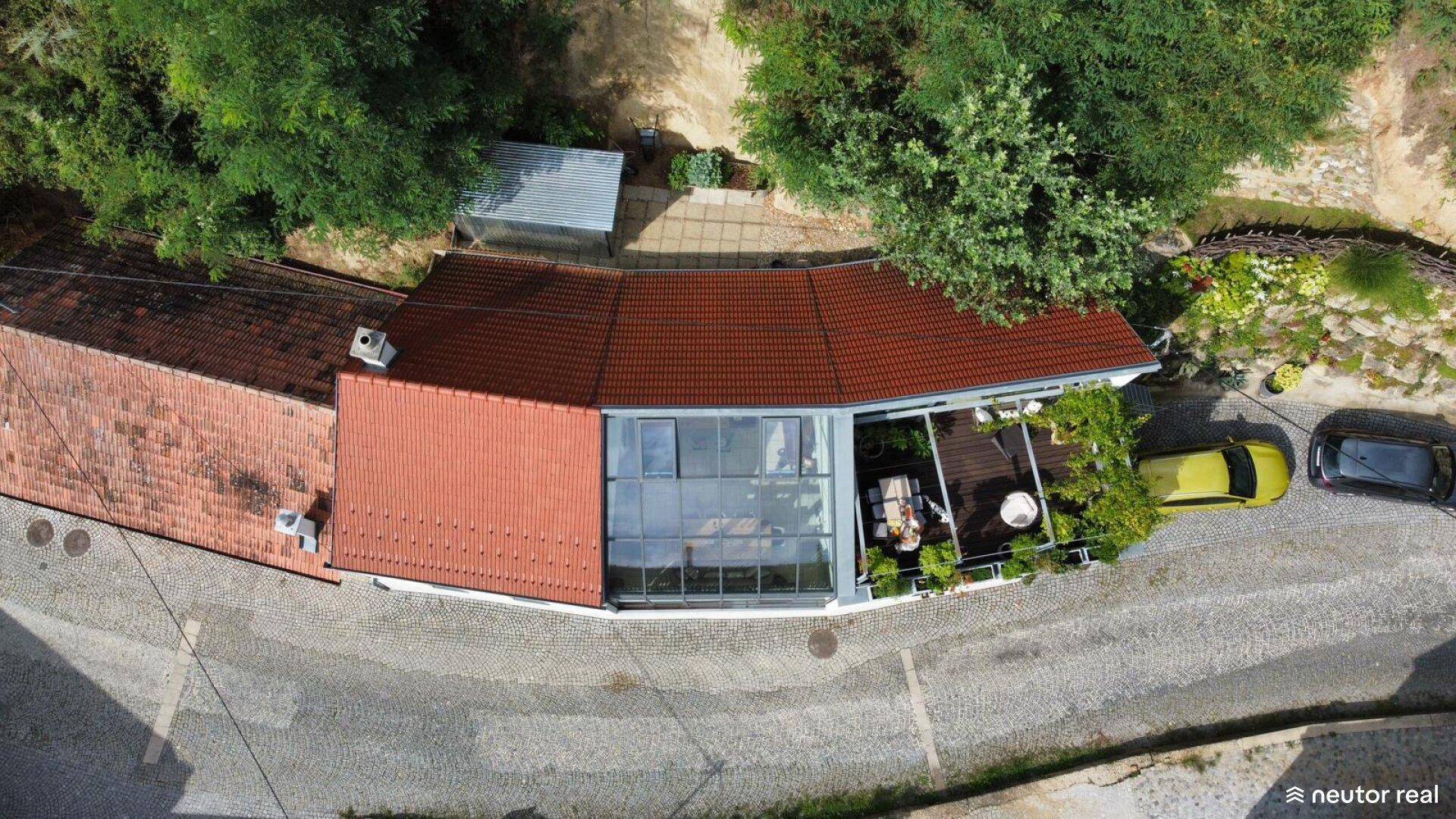 Luftaufnahme des Anwesens mit rotem Ziegeldach, Terrasse und umliegender grüner Landschaft.