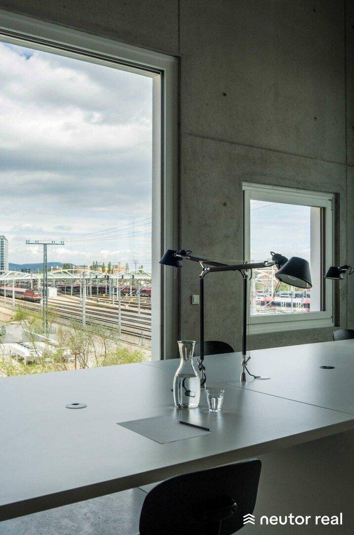 Heller Bürobereich mit großem Fenster, das einen weiten Blick auf Bahngleise und die Umgebung bietet.