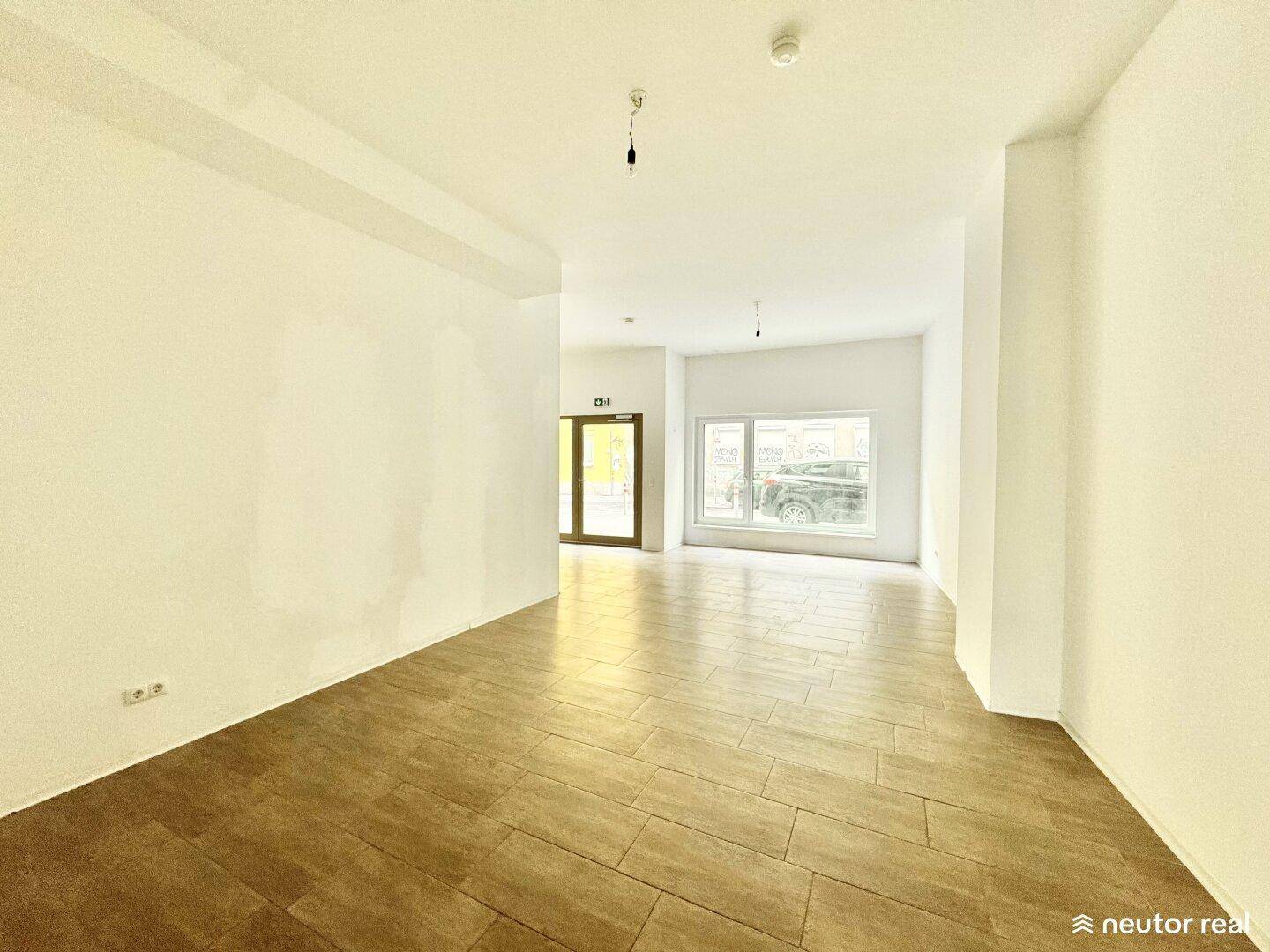 Geräumiger, heller Innenraum mit Fliesenboden und großen Fenstern, ideal für verschiedene Nutzungen.