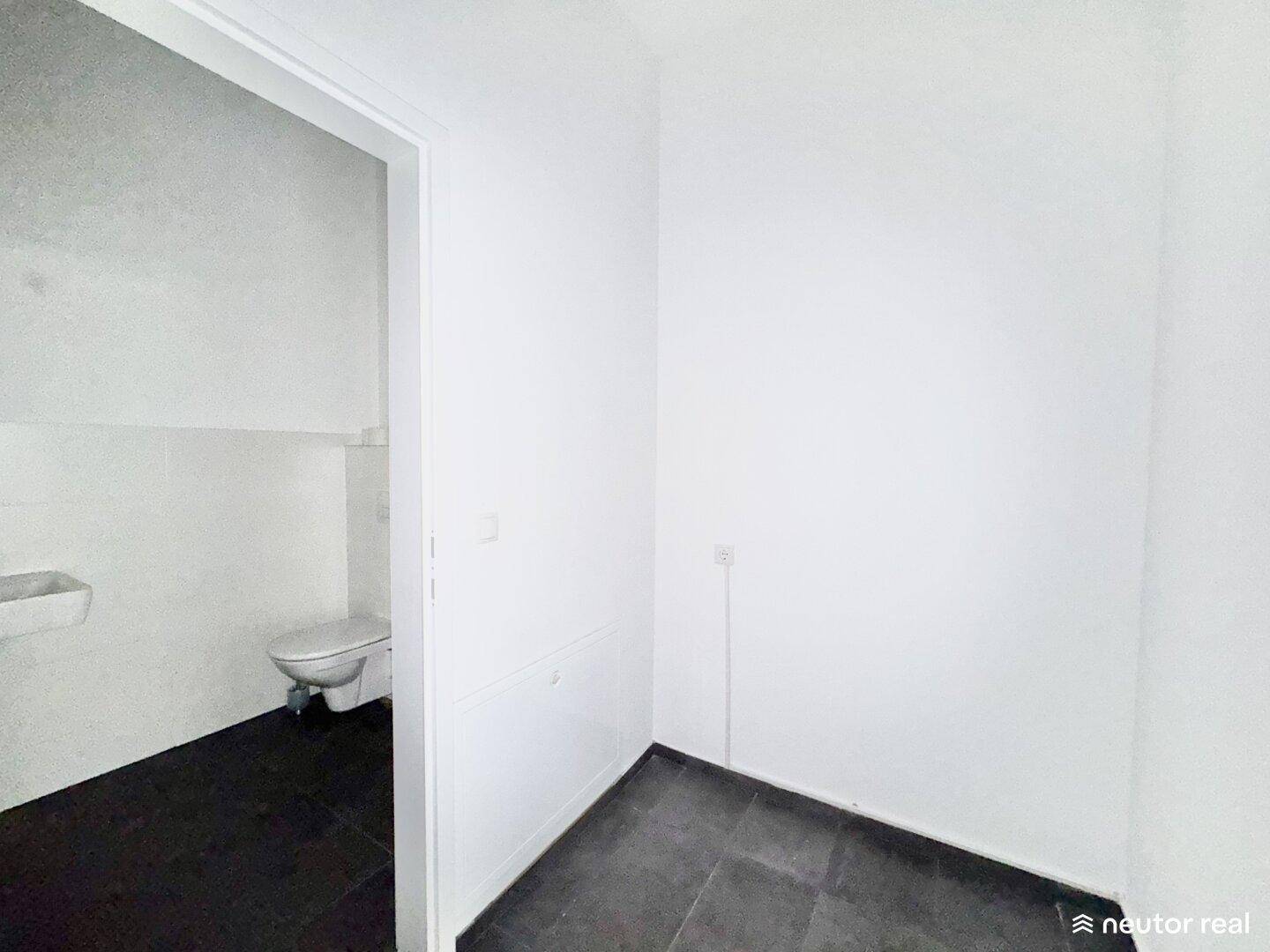 Kleines WC mit dunklem Fliesenboden und weiß gefliesten Wänden, funktional und sauber.