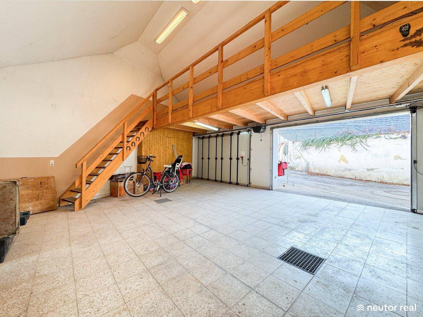 Geräumige Garage mit Fliesenboden, Holzkonstruktion und Rolltor.