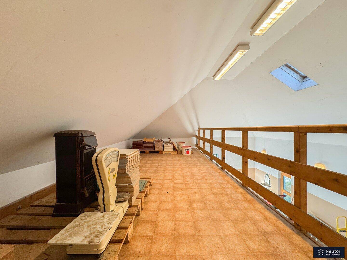 Offener Lagerbereich im Dachgeschoss mit Holzboden und Blick in die Garage.