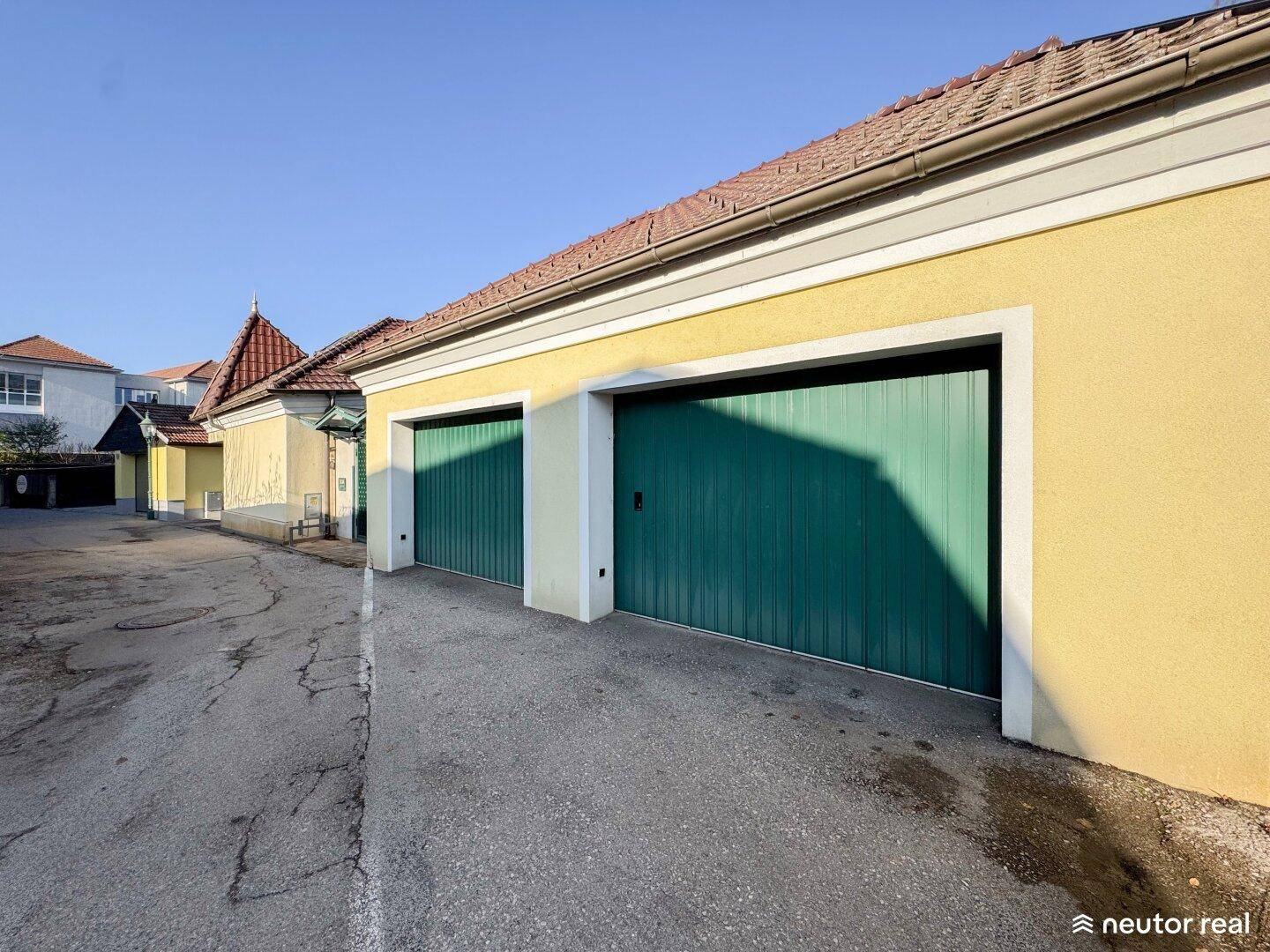 Doppelgarage mit grünen Toren und gepflasterter Zufahrt.