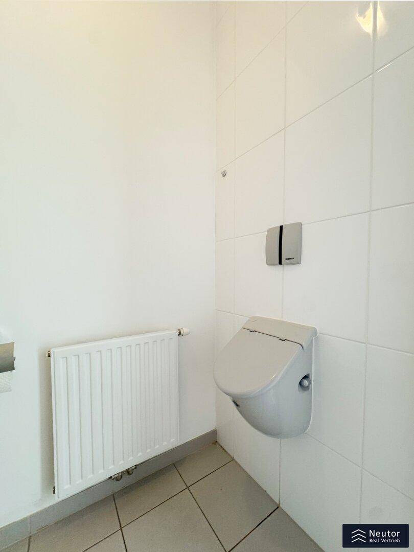 Modernes Wand-WC mit integriertem Spülkasten und weißen Fliesen in einem kleinen Raum.