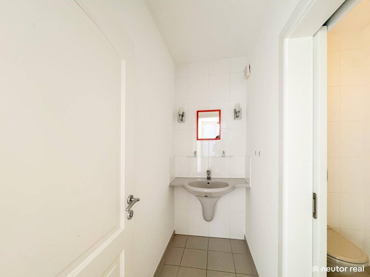Helles Gäste-WC mit Waschbecken, Spiegel und weißen Fliesen, funktional und sauber.