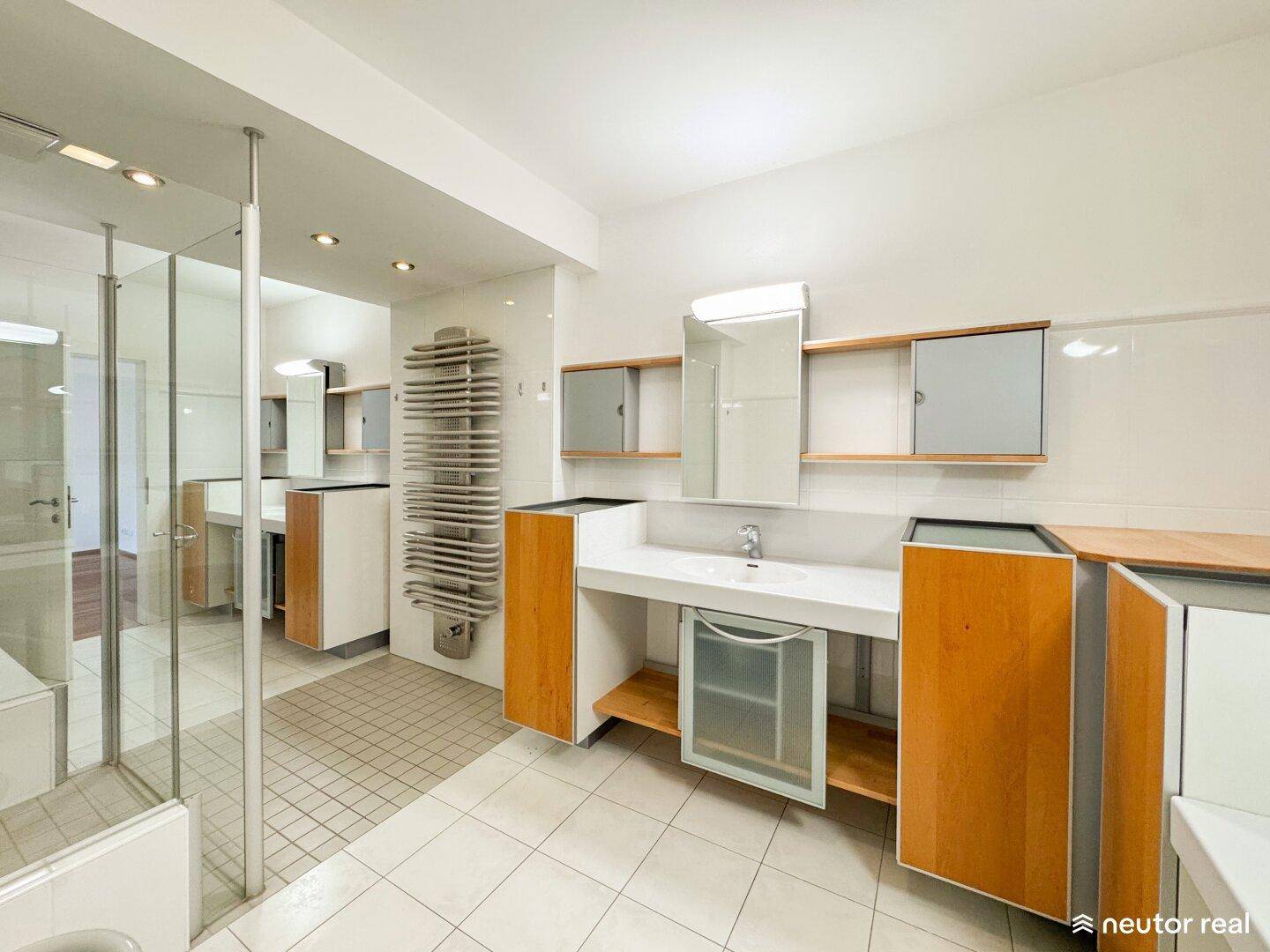 Modernes Badezimmer mit großem Waschtisch, Holzschränken und einer begehbaren Duschkabine.