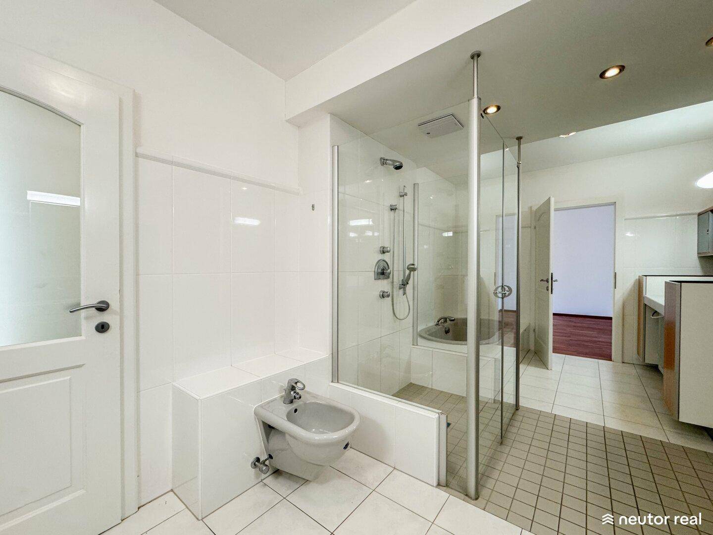 Helles Badezimmer mit Duschkabine, Bidet und weißen Fliesen, funktional und geräumig.